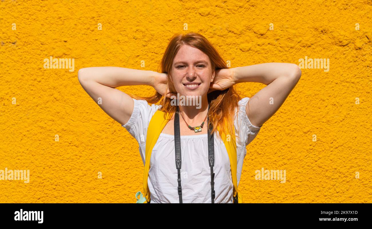 Bella donna con capelli rossi contro il muro giallo Foto Stock