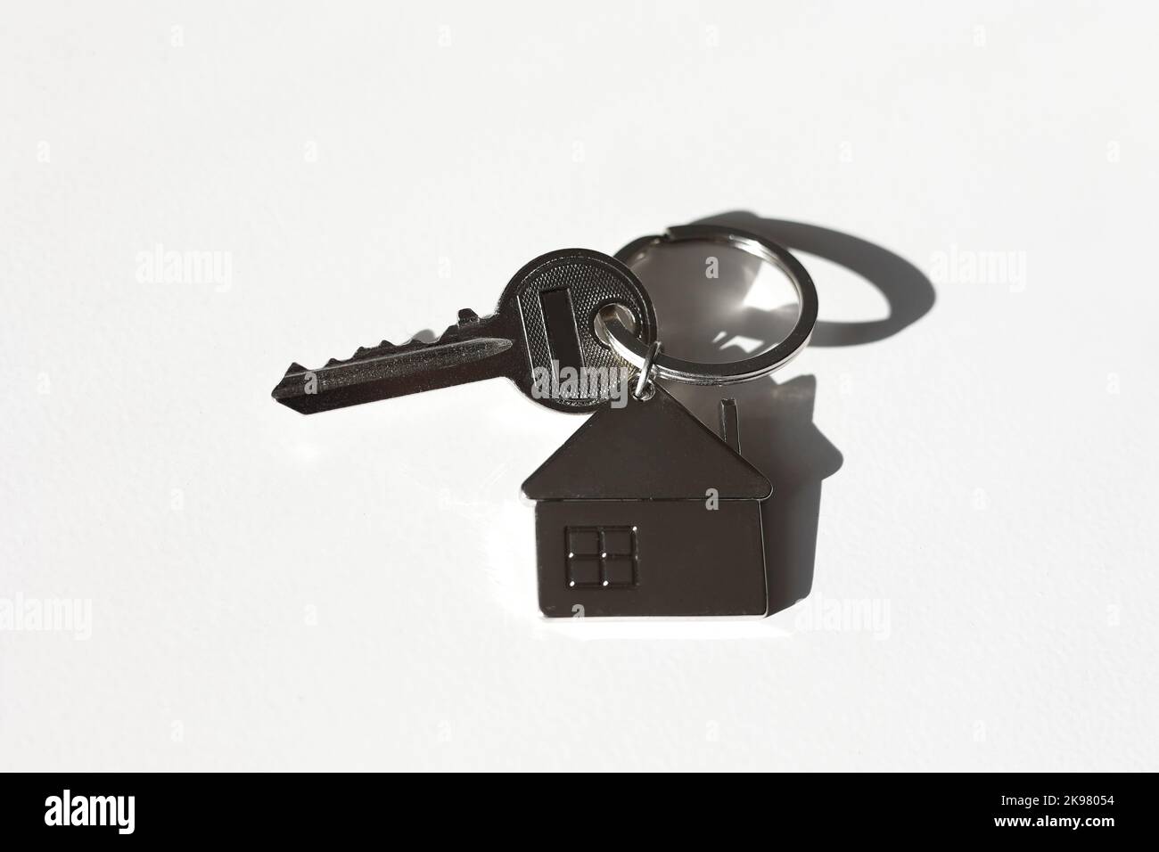 Portachiavi e portachiavi a forma di casa in metallo disposti su sfondo bianco con ombra. Commercio e assicurazione. Concetto di acquisto, vendita, locazione di vera esta Foto Stock