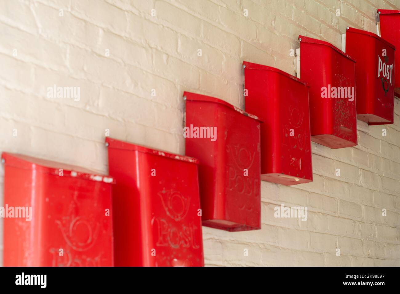 Più cassette postali, cassette postali o cassette postali in metallo rosso sono state fissate a una parete interna beige dell'edificio di appartamenti. Essi sono disposti in una cascata vicino Foto Stock