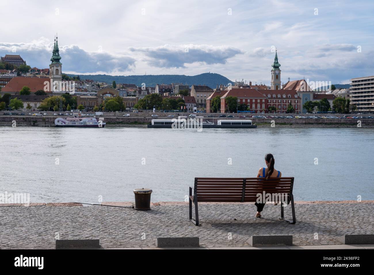 Budapest, Ungheria - 1st settembre 2022: Donna seduta su una panchina sulle rive del Danubio Foto Stock