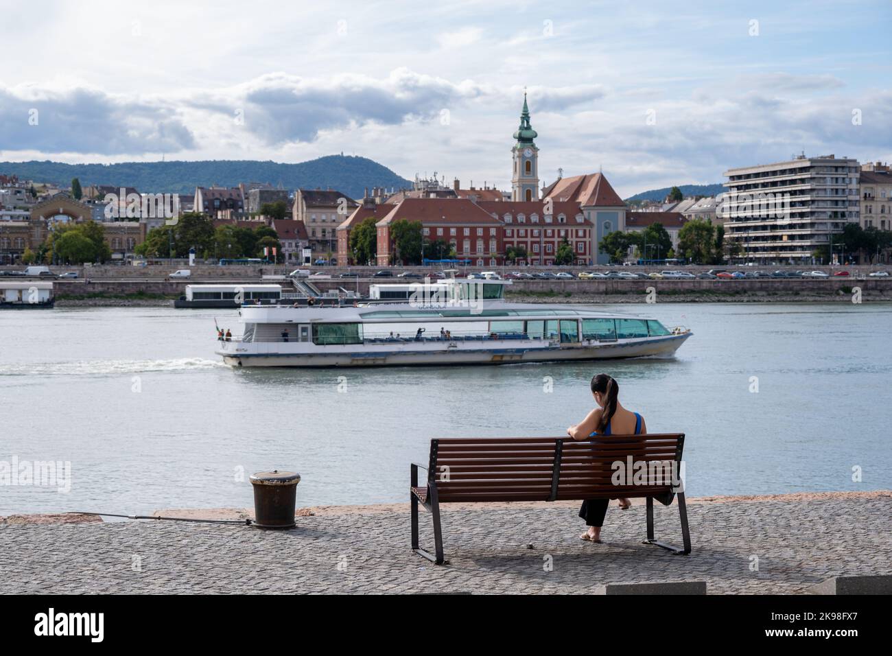 Budapest, Ungheria - 1st settembre 2022: Donna seduta su una panchina sulle rive del Danubio Foto Stock