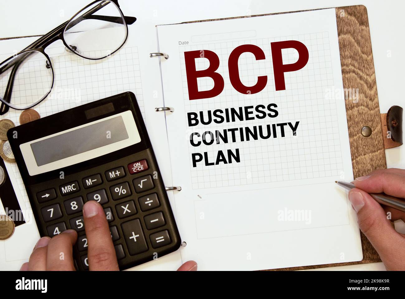 Su uno sfondo grigio chiaro si trovano una penna, un notebook verde e un biglietto bianco con il testo BCP Business Continuity Plan. Concetto aziendale. Foto Stock