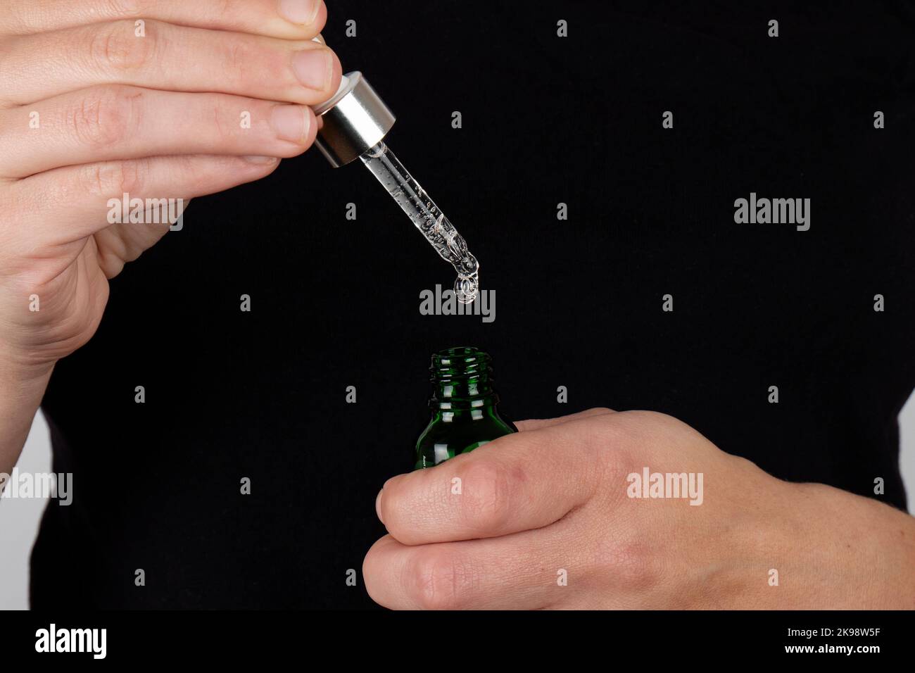 la mano tiene in mano una pipetta e un flacone di medicinale. Foto Stock