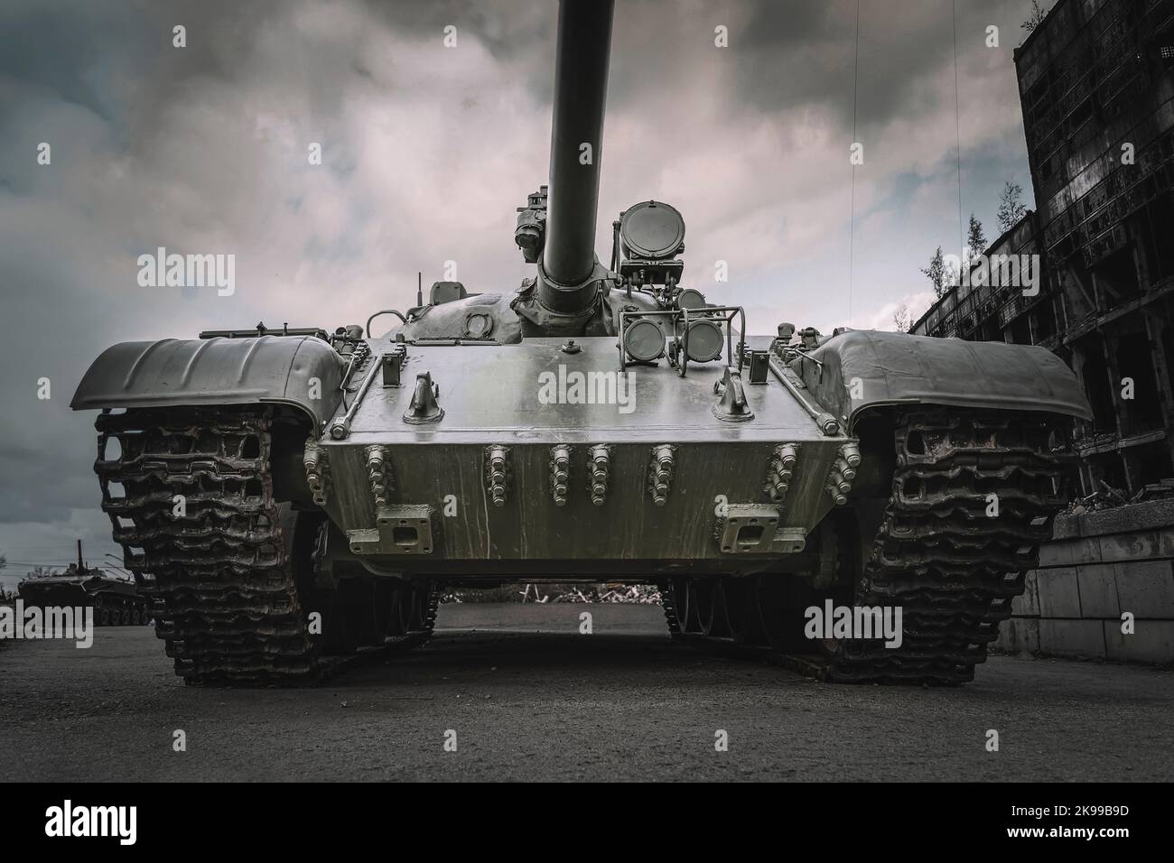 vecchio carro armato sovietico sullo sfondo di case distrutte. Il concetto di guerra in Europa. L'offensiva di pesanti veicoli corazzati per le strade della città Foto Stock