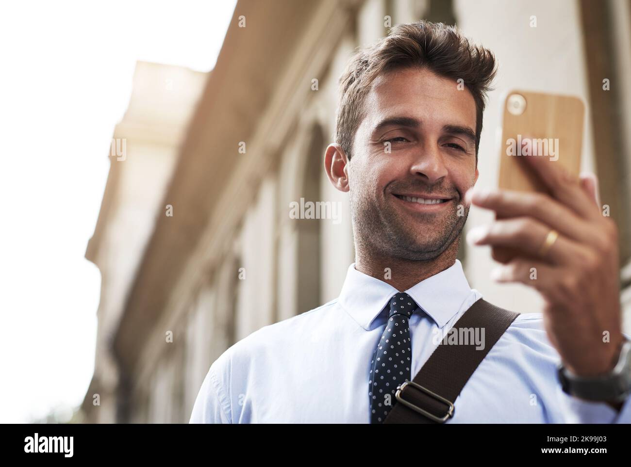 Gli piace camminare al lavoro, un bel giovane uomo d'affari che gli SMS sul cellulare mentre si recava al lavoro la mattina. Foto Stock