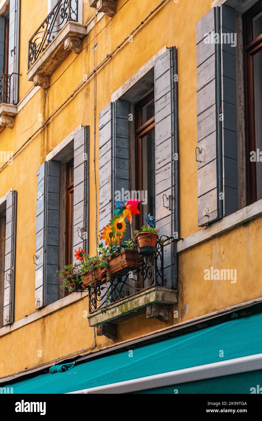 Una bella foto di fiori colorati su un balcone di un edificio giallo Foto Stock