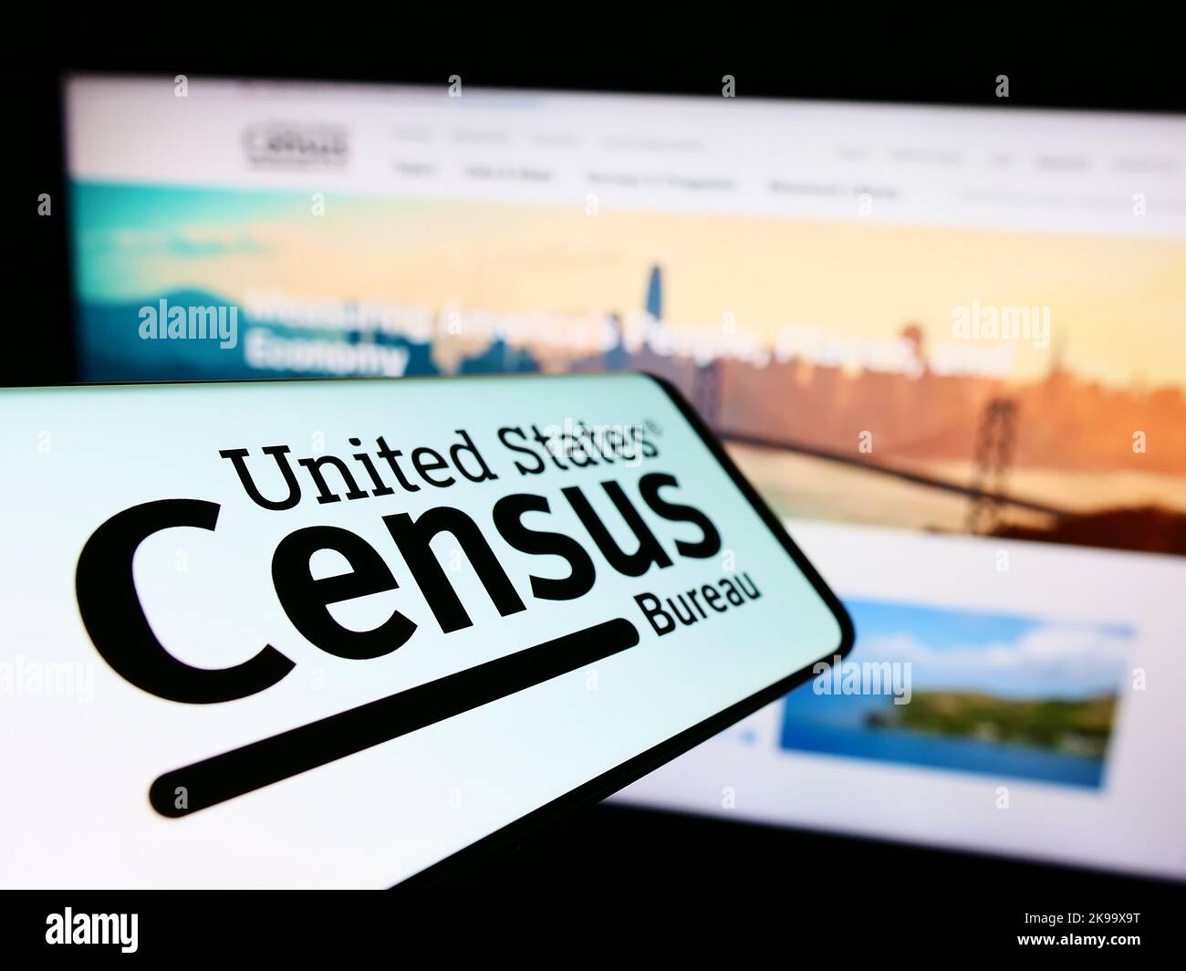 Smartphone con logo dell'agenzia statunitense United States Census Bureau (USCB) sullo schermo di fronte al sito Web. Messa a fuoco al centro a sinistra del display del telefono. Foto Stock