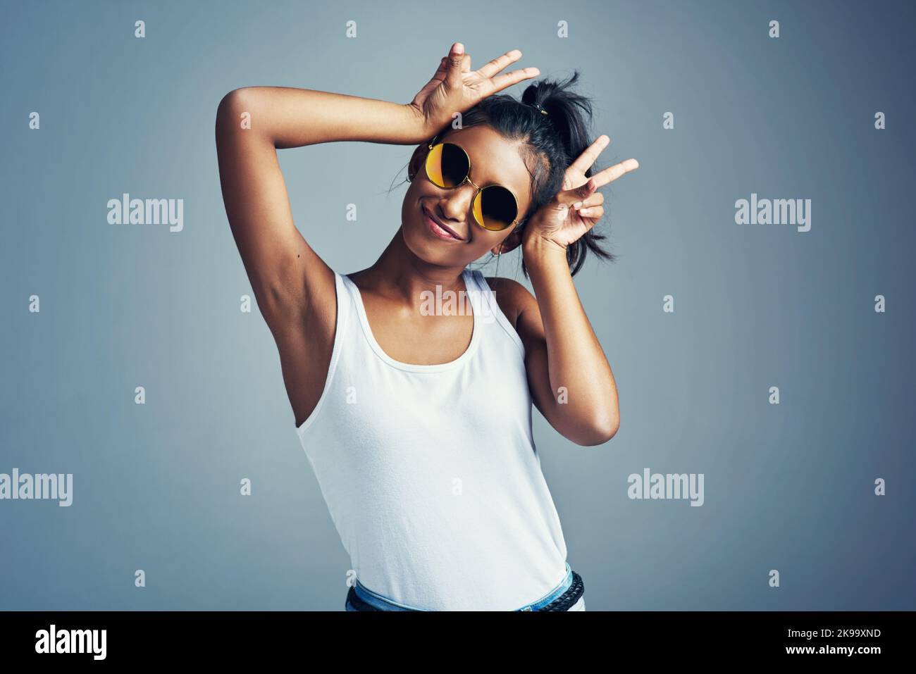 Shes sensazione funk e funky. Studio ritratto di una bella giovane donna gesturante con coniglietto orecchie su uno sfondo grigio. Foto Stock