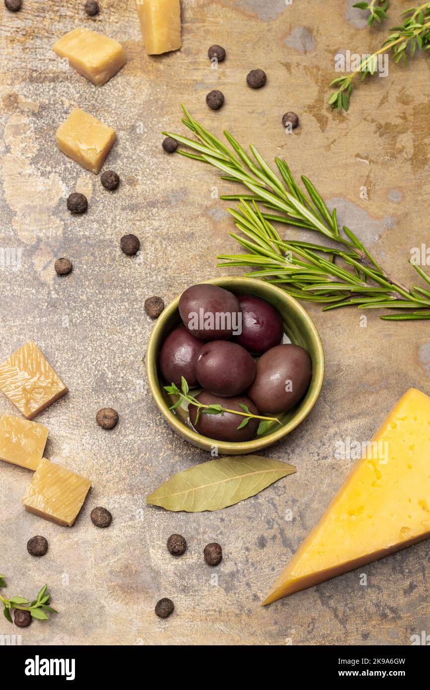 Olive in una ciotola, un rametto di rosmarino e pezzetti di formaggio. Giacitura piatta. Fondo in metallo arrugginito. Foto Stock