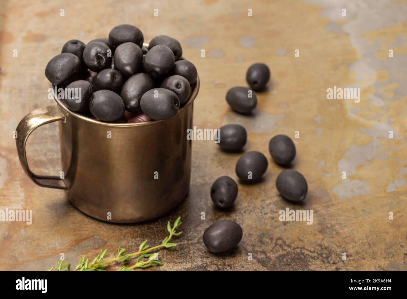 Olive nere in una tazza di metallo. Olive su fondo arrugginito. Vista dall'alto. Foto Stock