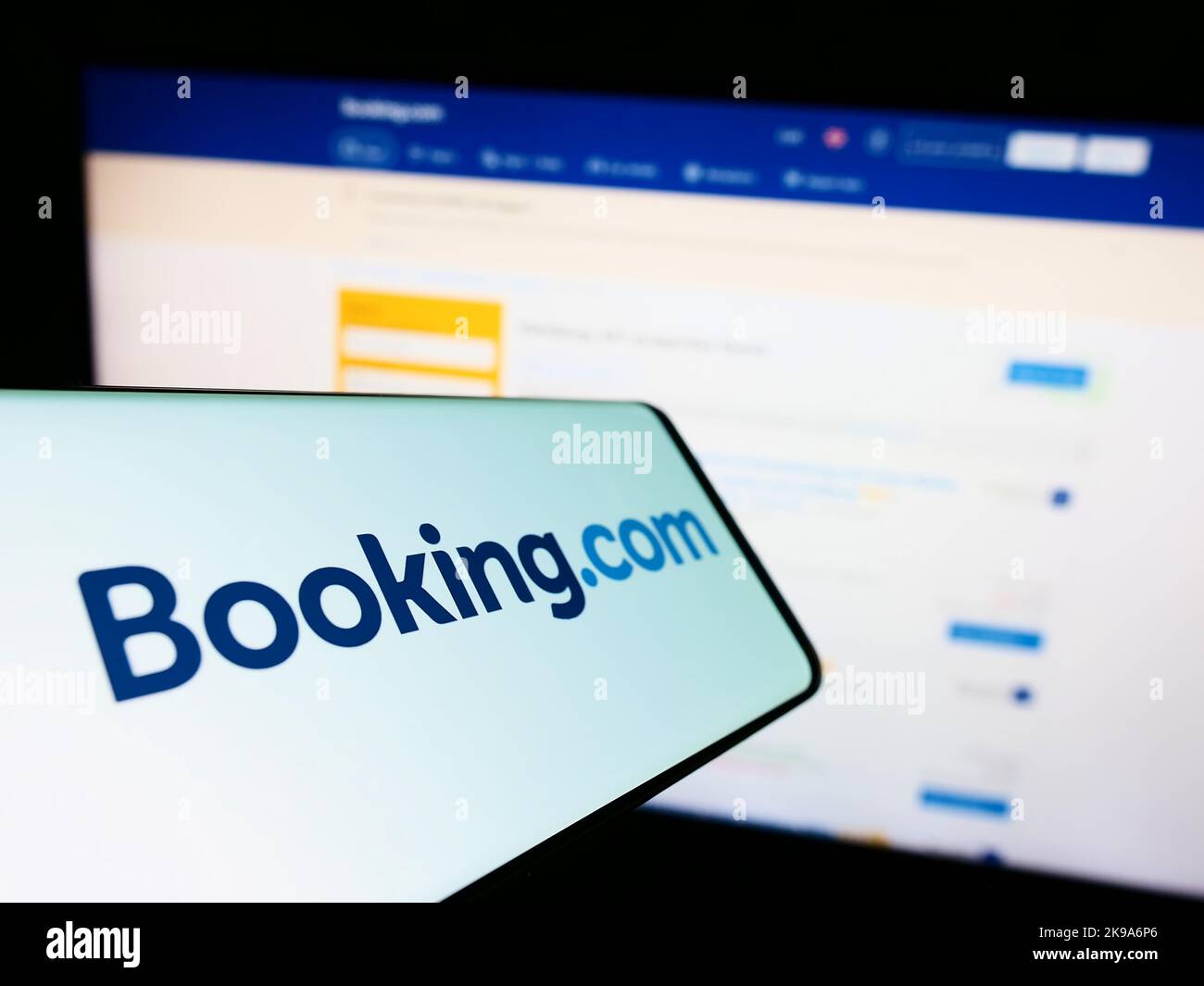 Cellulare con il logo dell'agenzia di viaggi online olandese Booking.com sullo schermo di fronte al sito web aziendale. Messa a fuoco al centro a destra del display del telefono. Foto Stock