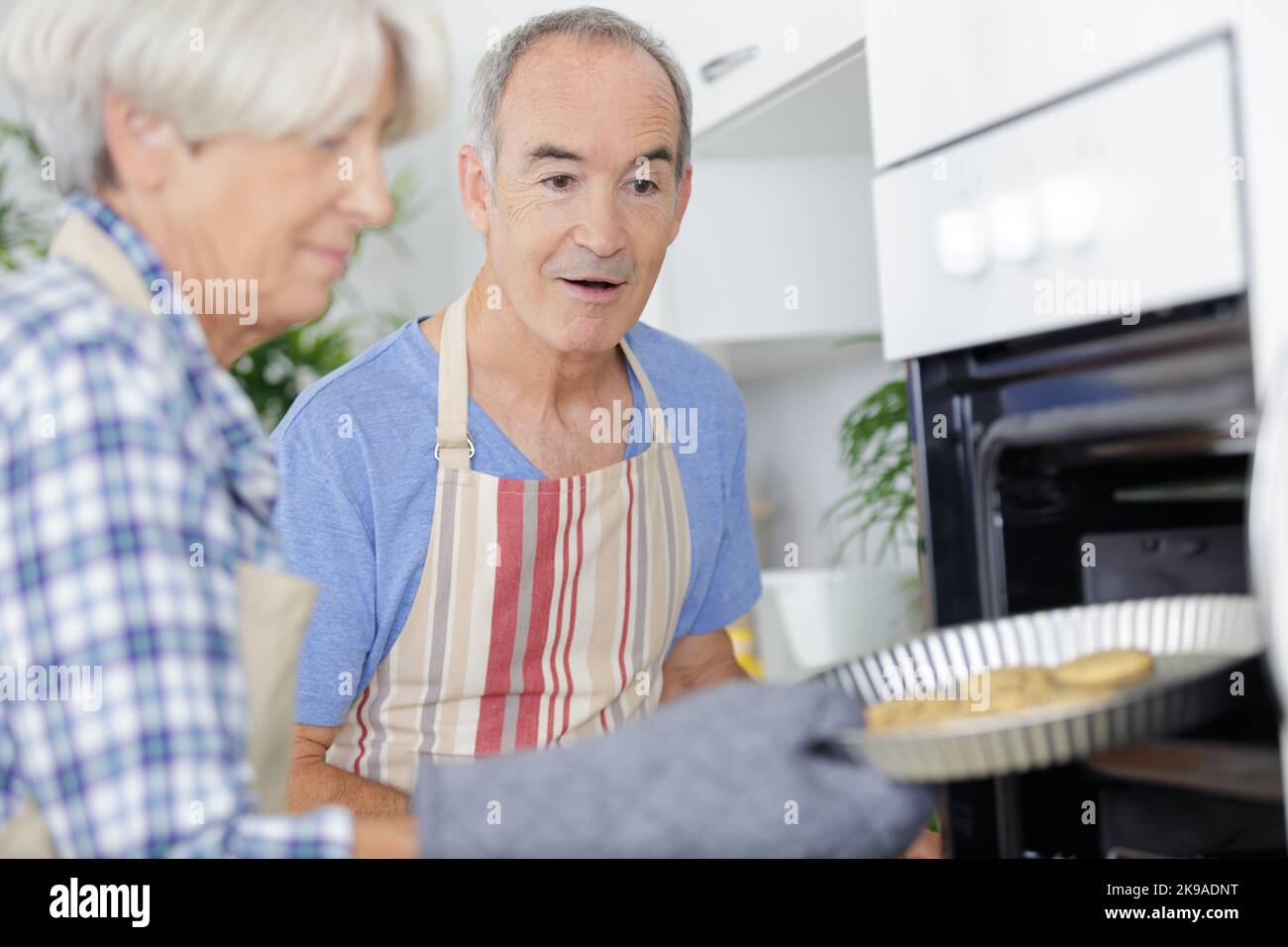 felice marito e donna che tiene vassoio con biscotti Foto Stock