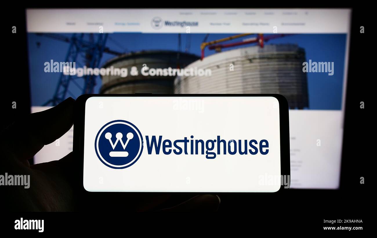 Persona che tiene il telefono cellulare con il logo di Westinghouse Electric Company LLC sullo schermo di fronte alla pagina web aziendale. Messa a fuoco sul display del telefono. Foto Stock