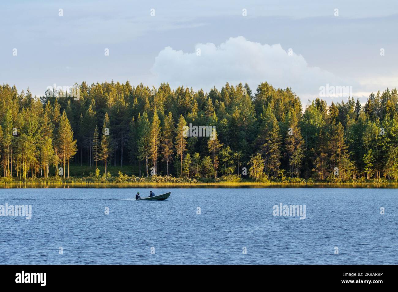 Un piccolo motoscafo con i pescatori in una serata di tarda estate vicino a Kuusamo, Finlandia settentrionale Foto Stock