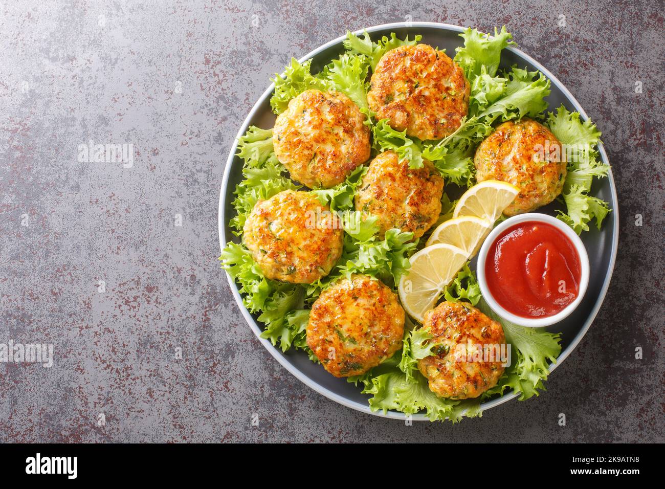 succulenta e deliziosa cotoletta di pollo fritta con formaggio, carote, zucchine ed erbe in un piatto sul tavolo. Vista orizzontale dall'alto Foto Stock