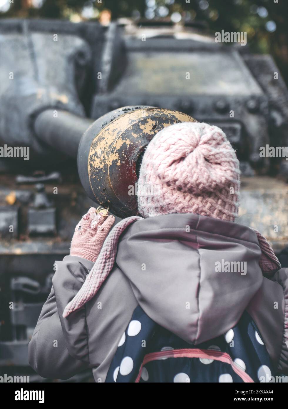 Ragazza che guarda giù il barile del vecchio carro armato. Foto Stock