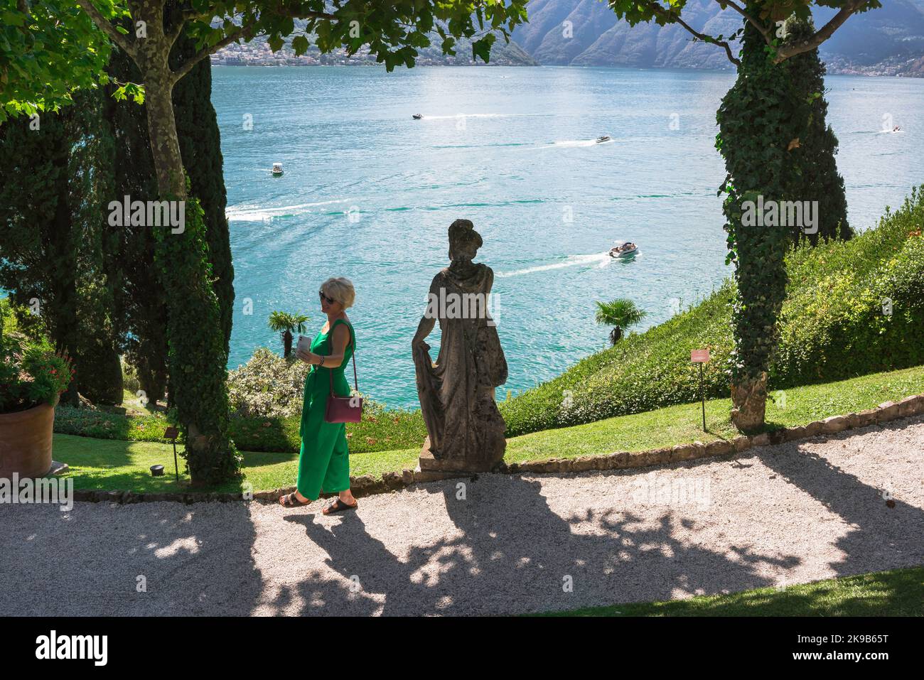 Viaggio femminile, vista in estate di una donna che scatta una foto di se stessa sullo sfondo del Lago di Como, Lombardia, Italia Foto Stock