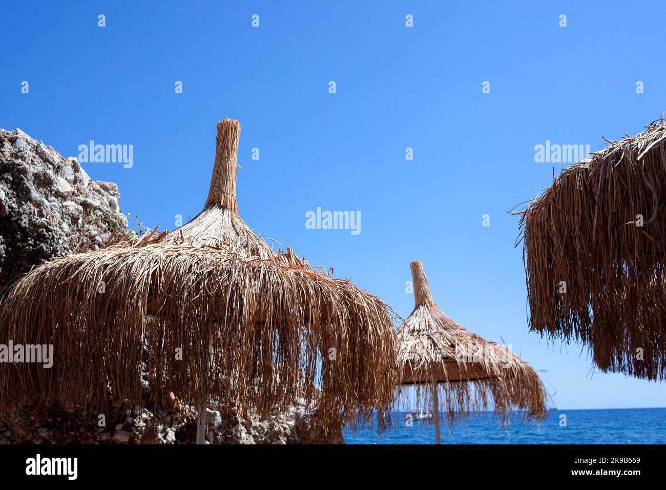 Ombrello di paglia o capanna di paglia con splendida vista sul cielo sulla spiaggia tropicale. Ombrelloni di paglia da spiaggia contro il cielo blu chiaro Foto Stock