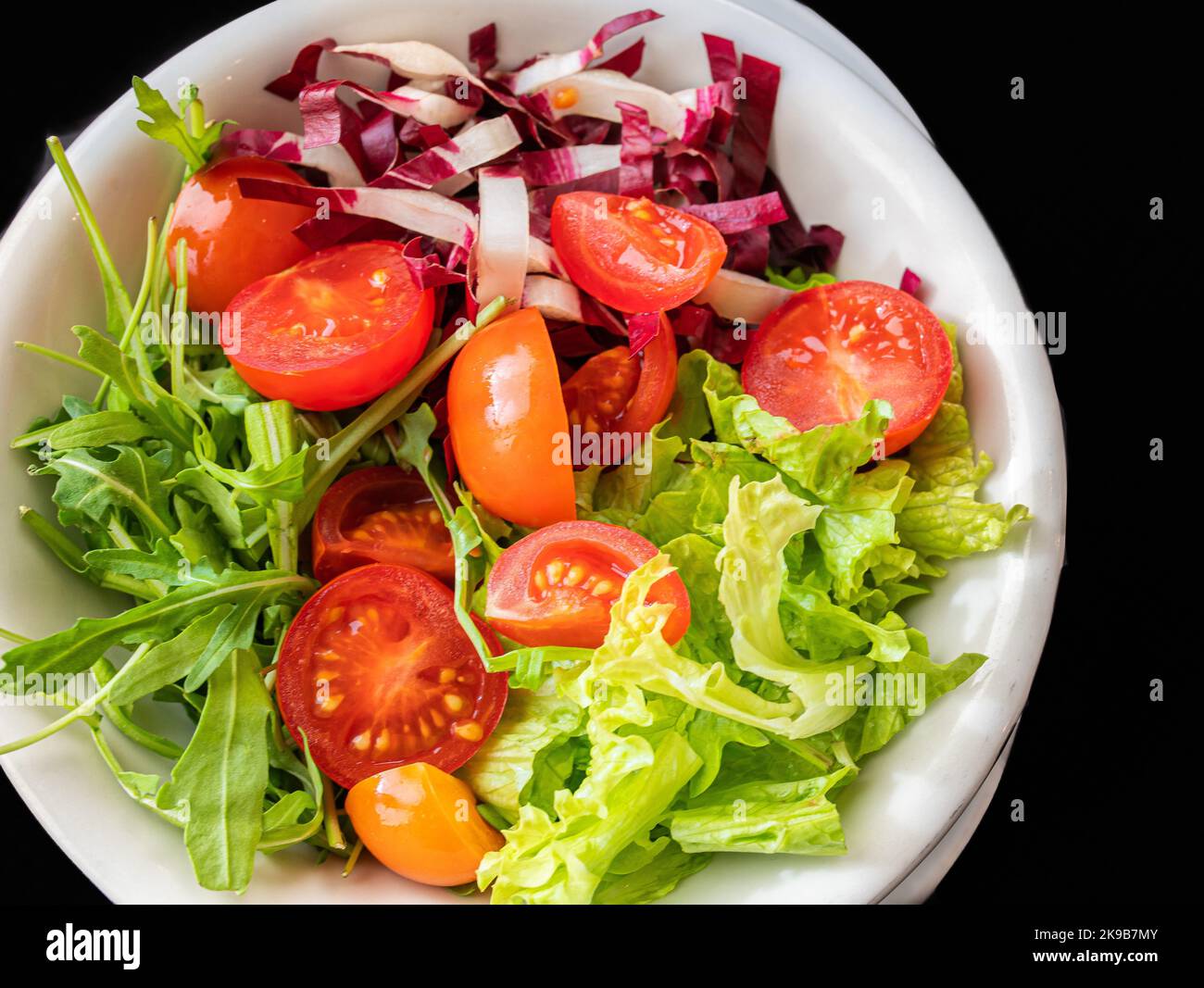 Insalata mista con lattuga, pomodoro e foglie di rucola fresca. Piatto vegetariano. Foto Stock