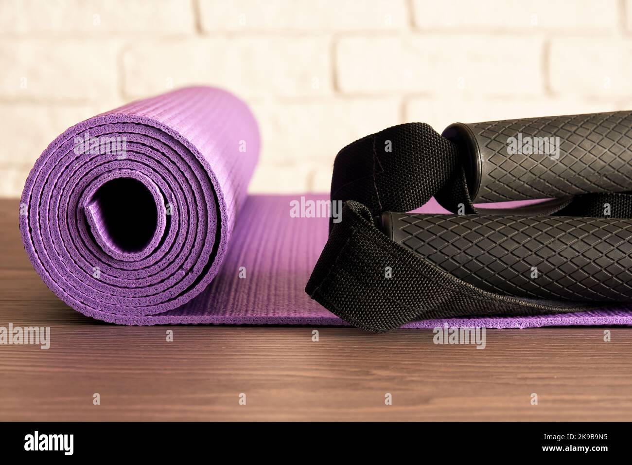 Tappetino fitness, maniglie e corde sul pavimento nella moderna palestra. Accessori per allenamento e aerobica Foto Stock