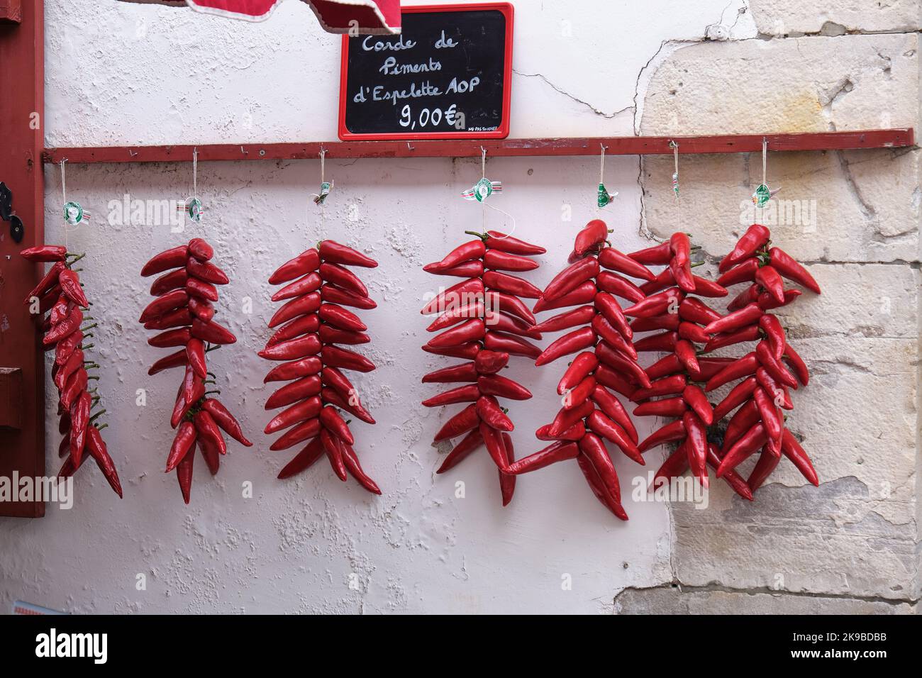 Peperoni rossi in grappoli appesi su un muro bianco durante l'annuale festa del pepe di Espelette in Francia Foto Stock