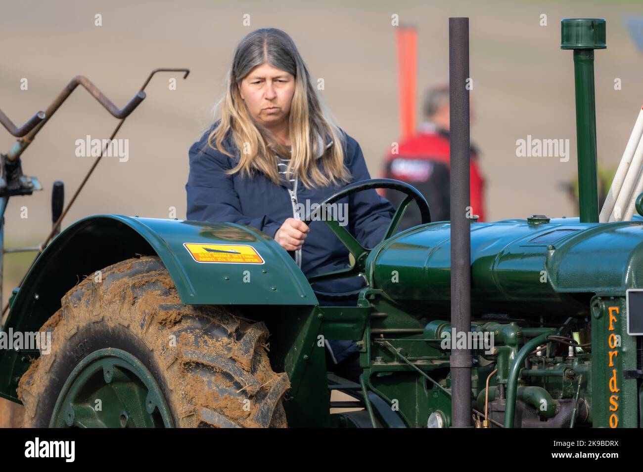 Conducente di trattore femmina in corrispondenza di un abbinamento di aratura. Medstead, Hampshire, Regno Unito Foto Stock