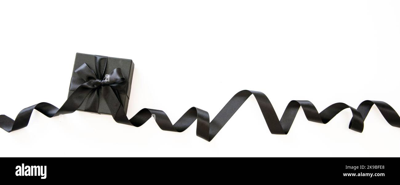 Banner di vendita del Black Friday. Confezione regalo con nastro nero riccio satinato isolato su sfondo bianco, spazio copia, modello di vendita Foto Stock