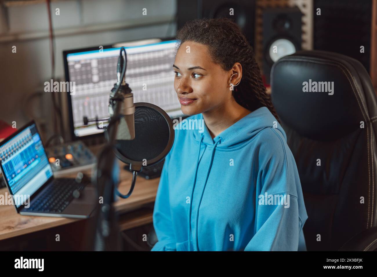 Donna etnica affascinante, presentatore radio con eleganti Dreadlocks lavorando in uno studio di registrazione audio di trasmissione Foto Stock