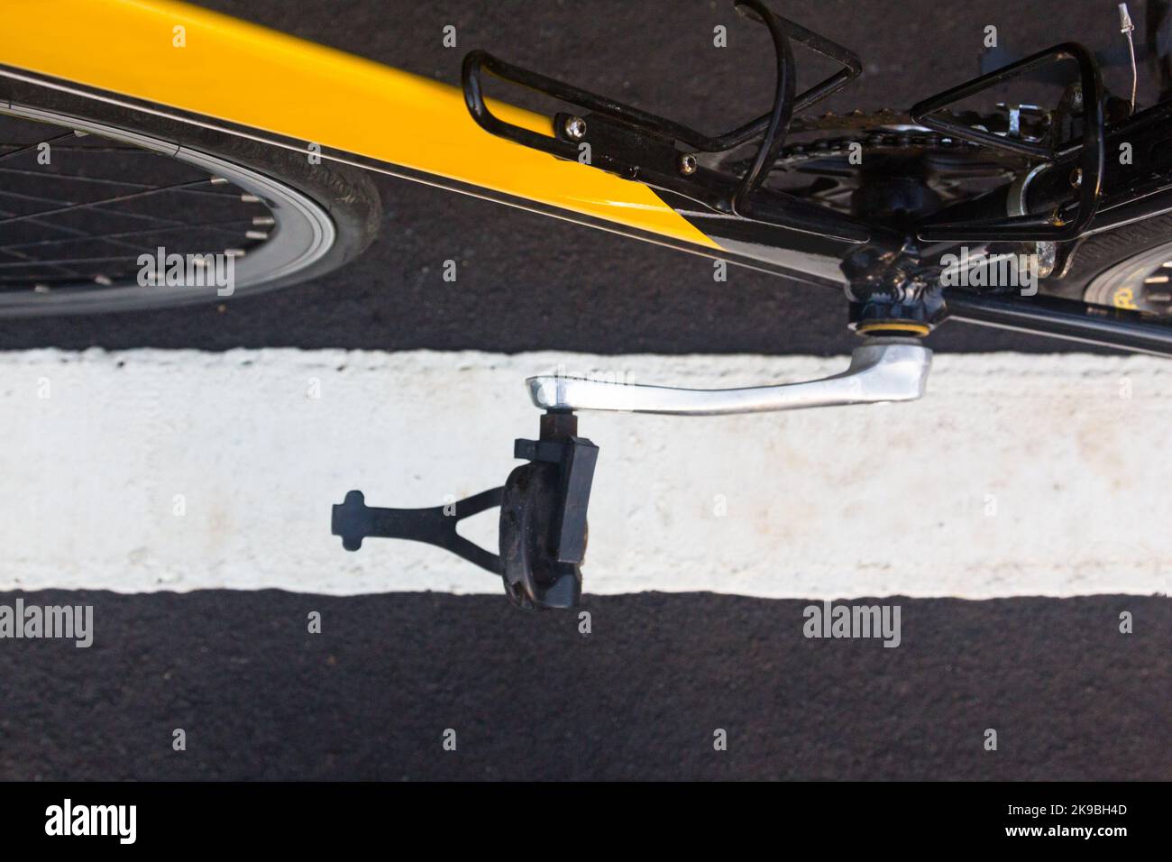 Una bici da corsa gialla e nera con un pedale lungo una linea Foto Stock