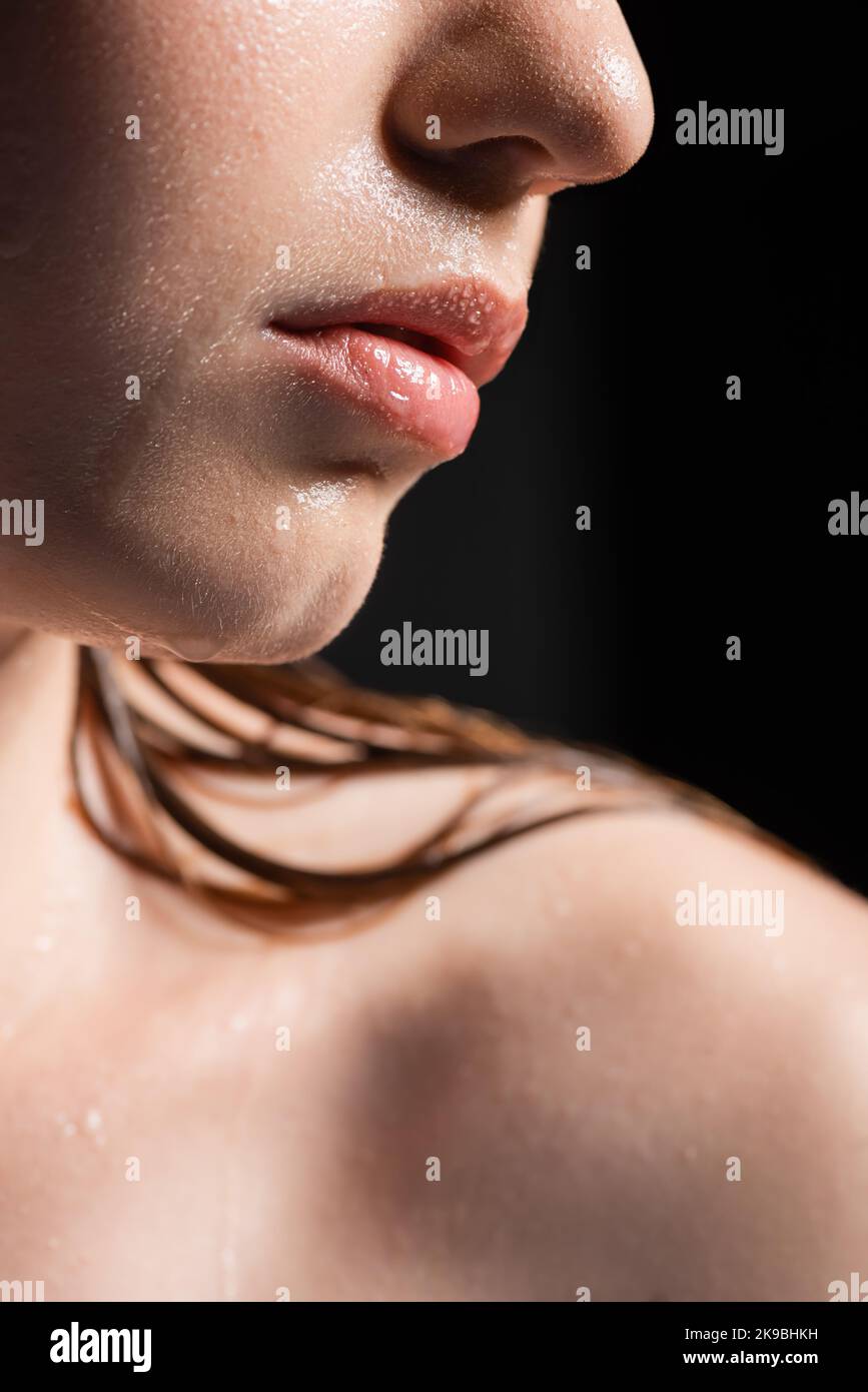 Vista ravvicinata della donna con pelle bagnata e labbra isolate sul nero Foto Stock