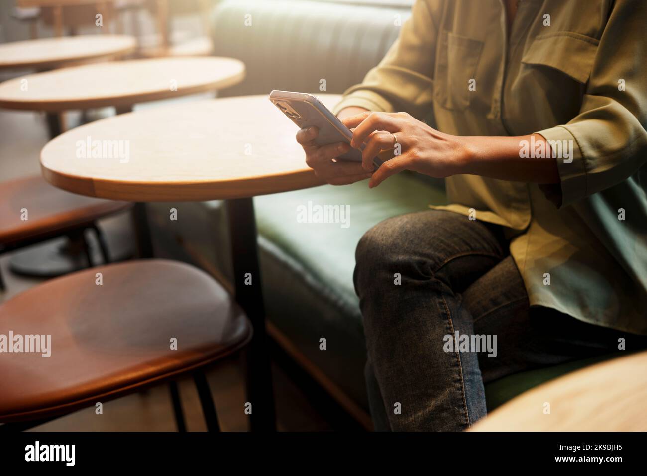 Primo piano della mano di una donna con uno smartphone durante la pausa caffè. Foto Stock