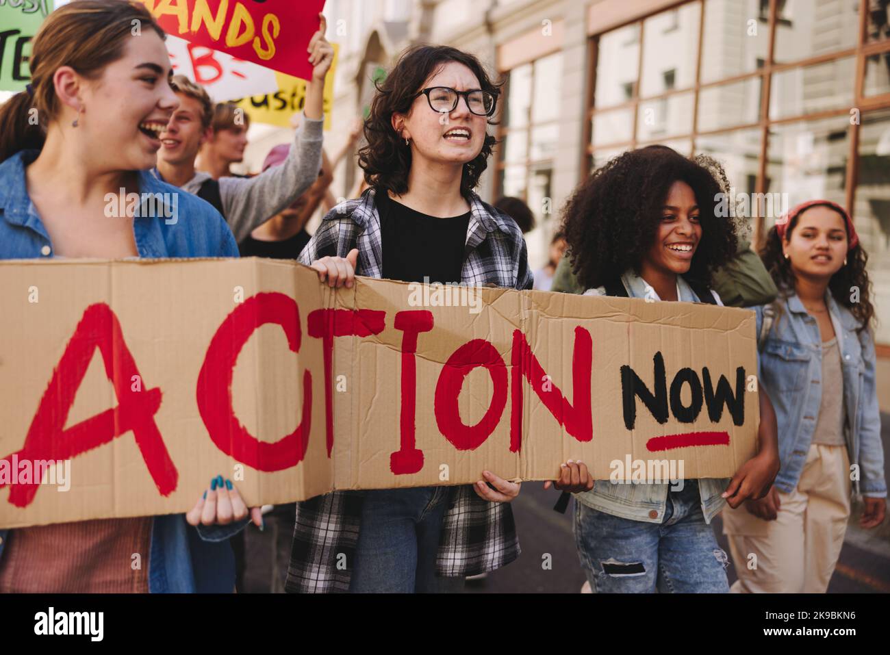 Gruppo di giovani multiculturali che si batte per l'azione climatica nella città. Attivisti giovani felici che tengono una bandiera mentre marciano contro il clima Foto Stock