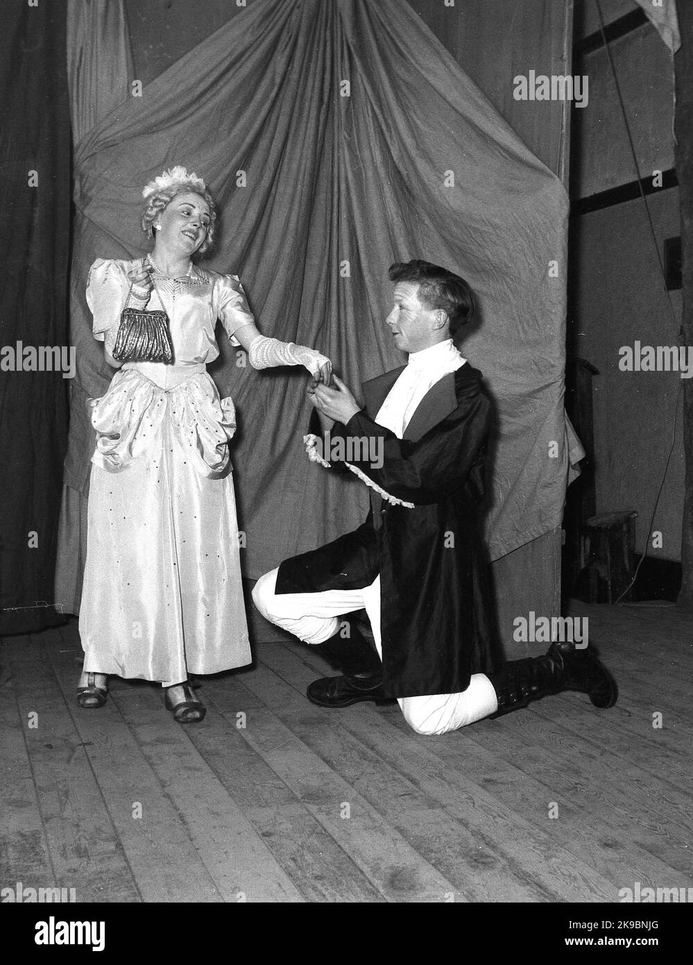 1955, storico, febbraio, una giovane donna e attori maschi nei loro costumi che appaiono nella pantomina, Robin Hood, Leeds, Inghilterra, UK. Posando sul palco per una foto, Foto Stock