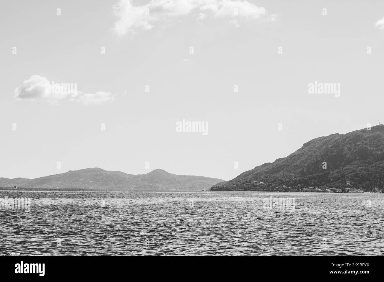 Corfù, Grecia. Splendida vista sull'acqua con enormi montagne sulla riva sotto un cielo blu. Foto Stock
