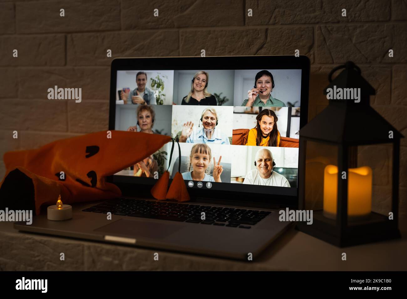 Gruppo di persone felice di vedersi a Halloween virtuale festa. Computer portatile al tavolo da cucina decorato, la mano ondeggiante e saluto gli amici a. Foto Stock