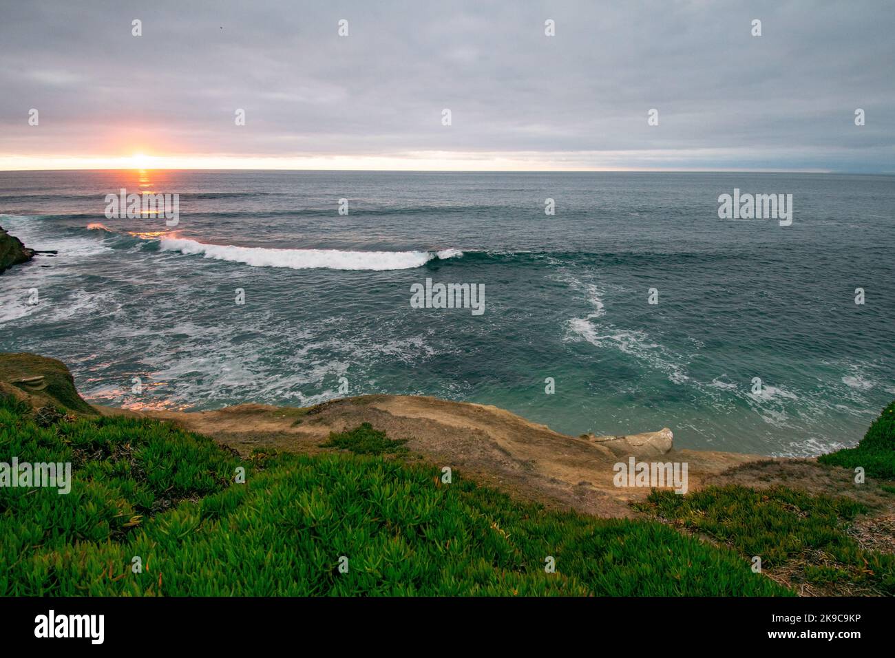 Splendida foto al tramonto scattata a la Jolla, California, che mostra scogliere, onde e una baia. Fotografia al tramonto con verde, blu e arance. Foto Stock