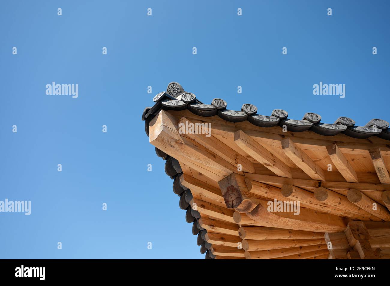 Tradizionale angolo orientale del tetto del tempio in legno con piastrelle nere e cielo blu Foto Stock