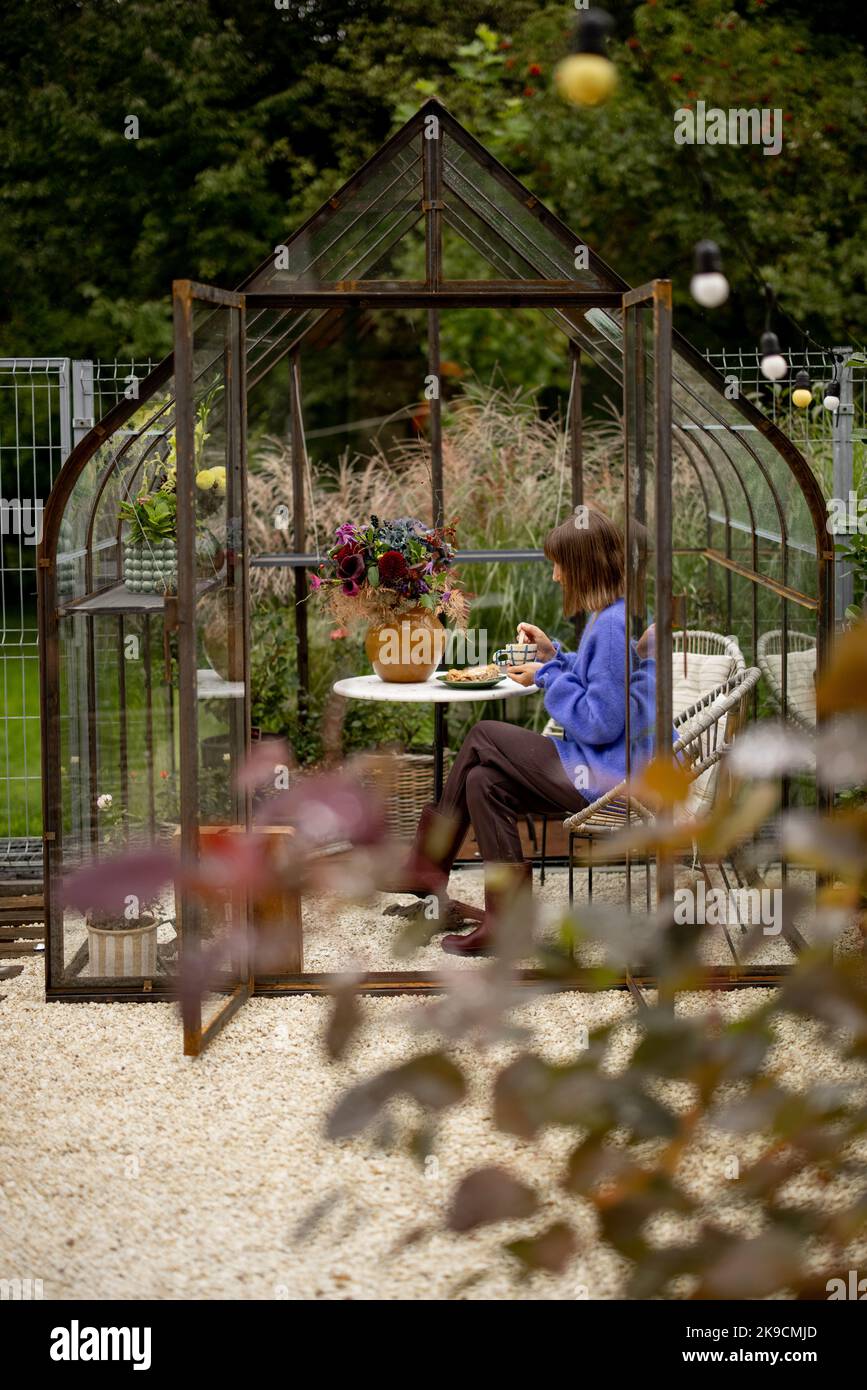 Donna che si rilassa in serra in giardino Foto Stock