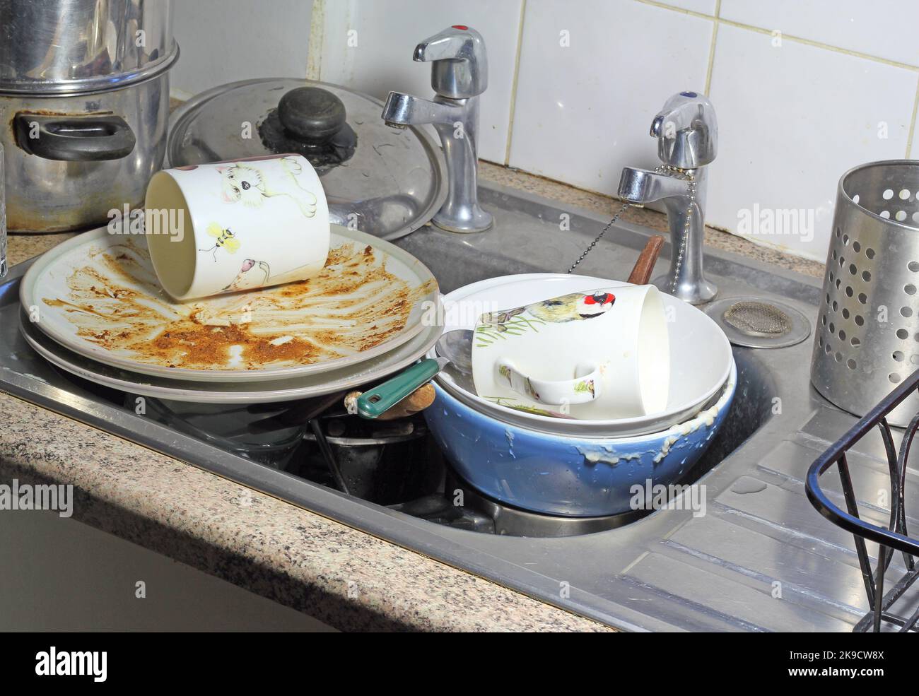 Stoviglie sporche, incluse tazze e piatti in un lavandino, in attesa di essere pulite o lavate. Foto Stock