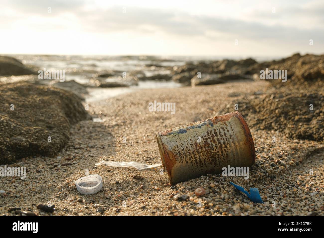 Scatola metallica arrugginita usata e residui di plastica gettati sull'ecosistema marino, danni all'inquinamento ambientale Foto Stock