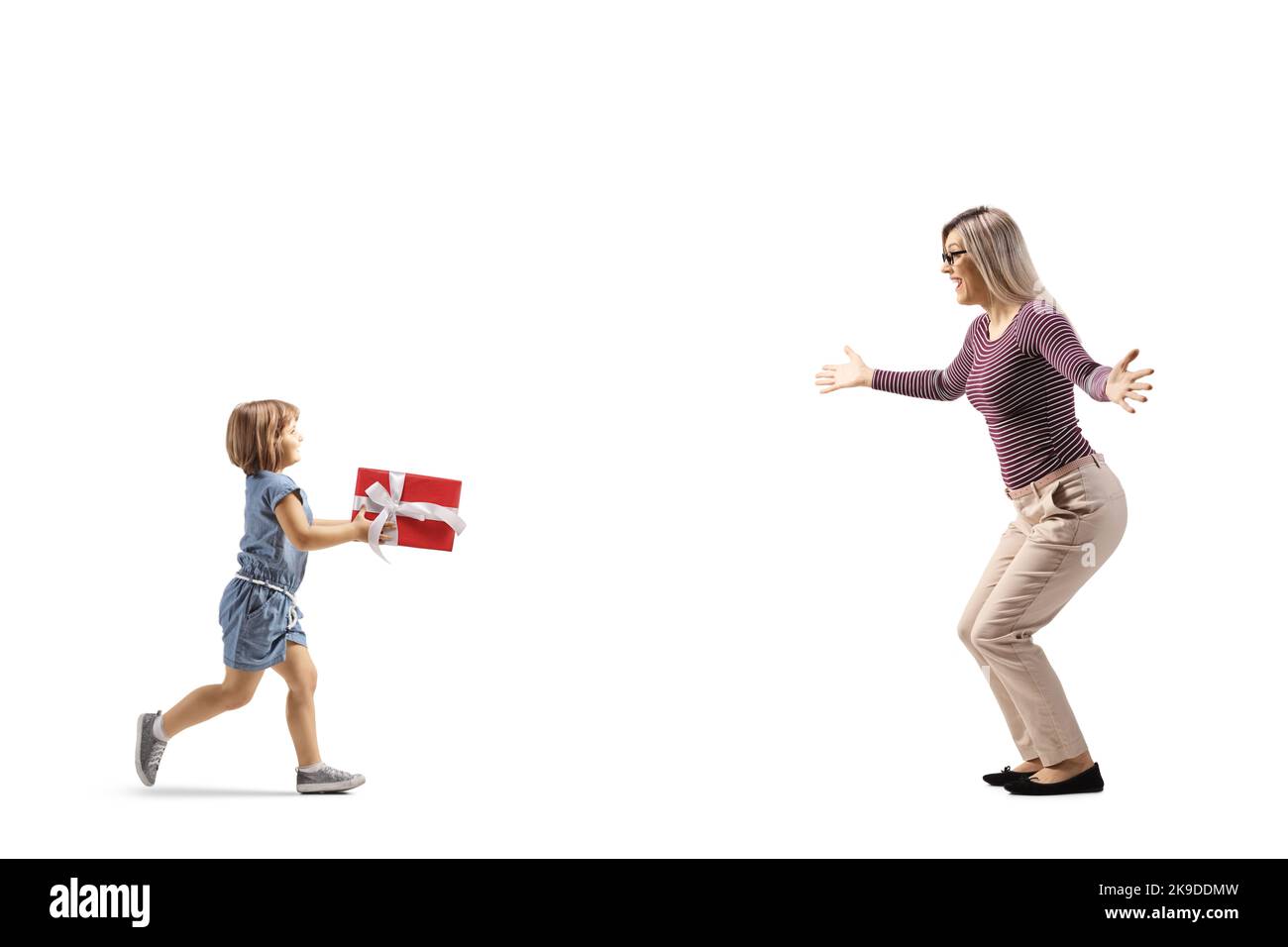 Profilo a tutta lunghezza girato di una bambina che corre verso una donna e che porta un presente isolato su sfondo bianco Foto Stock