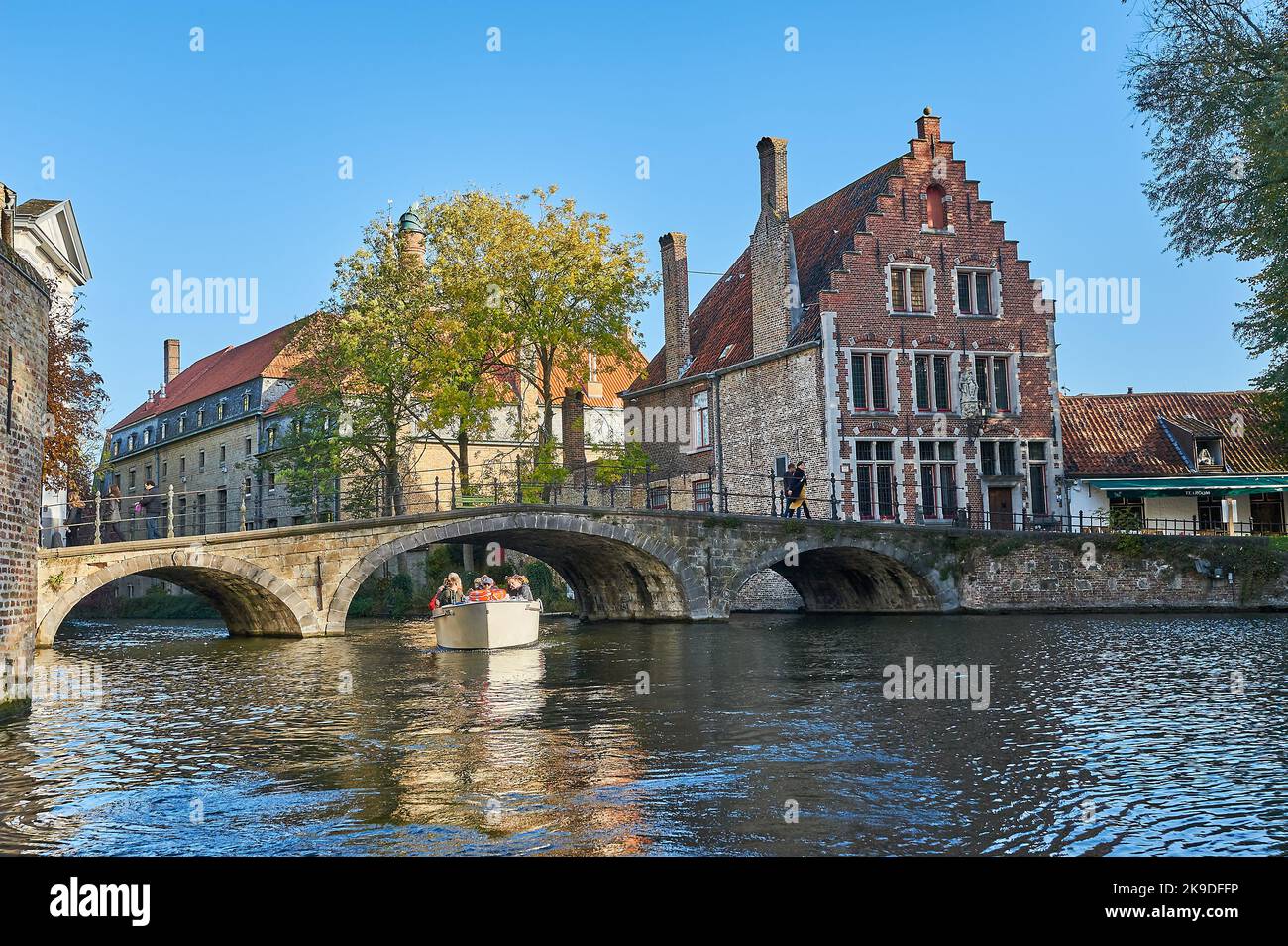 Bruges, le Fiandre, il Belgio e un piccolo ponte ad arco in pietra portano Begijnhof attraverso il canale della città Foto Stock