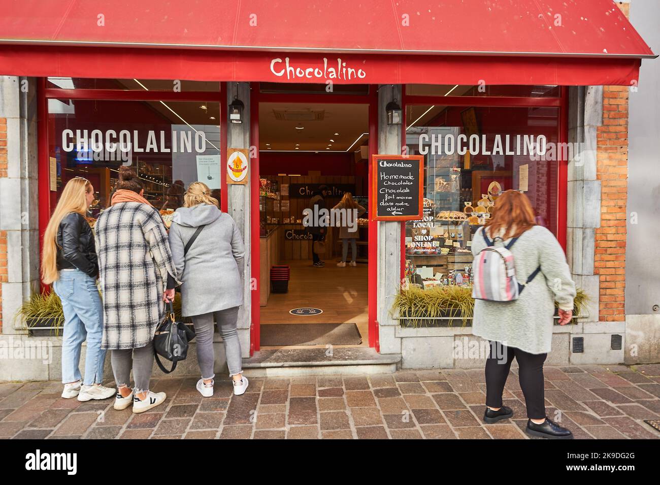 Bruges (Brugge) in Belgio e un gruppo di turisti guardano alla finestra di uno dei famosi negozi di chocloate della città Foto Stock