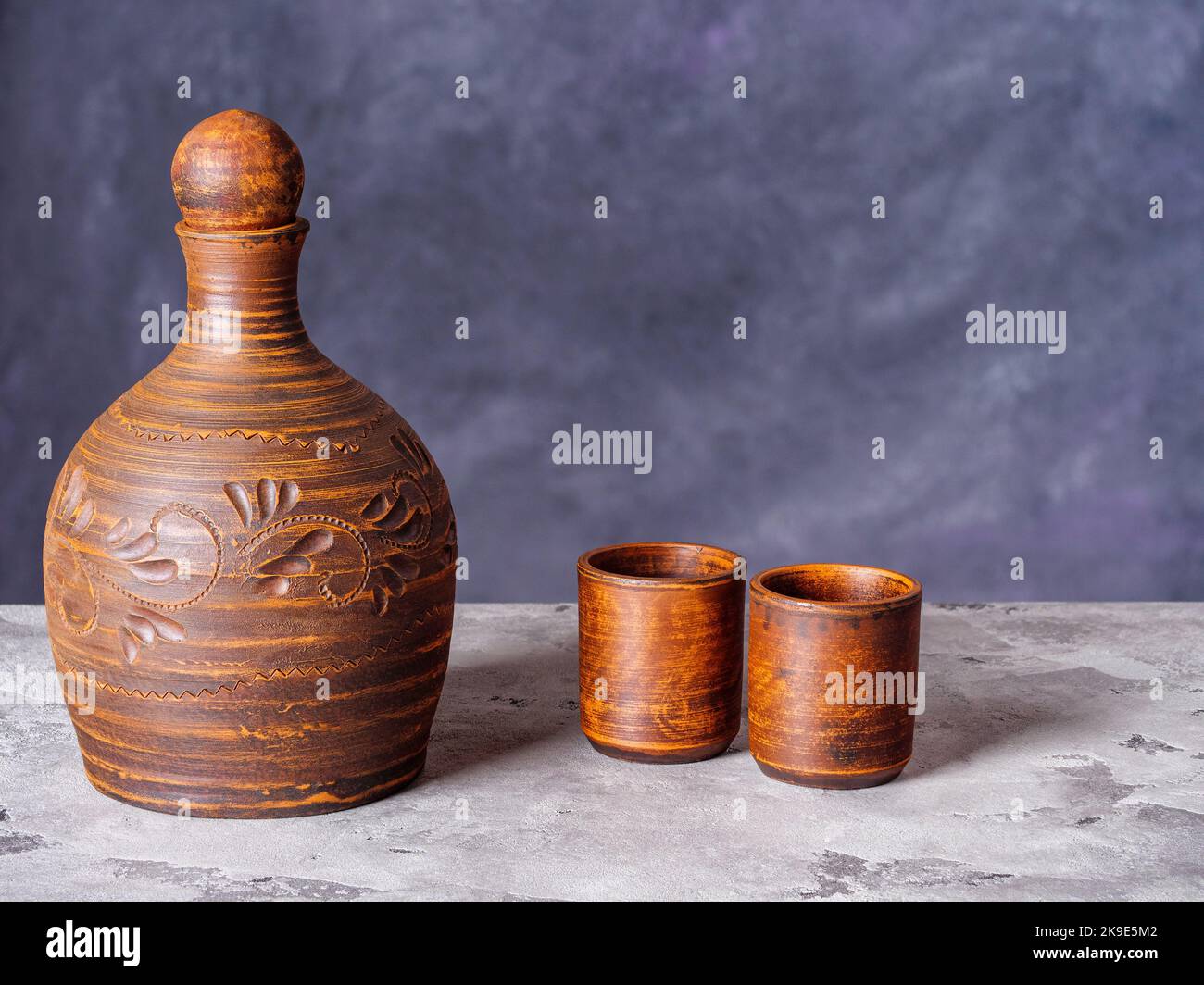 Caraffa in argilla e due bicchieri in ceramica su uno sfondo in stile grunge Foto Stock