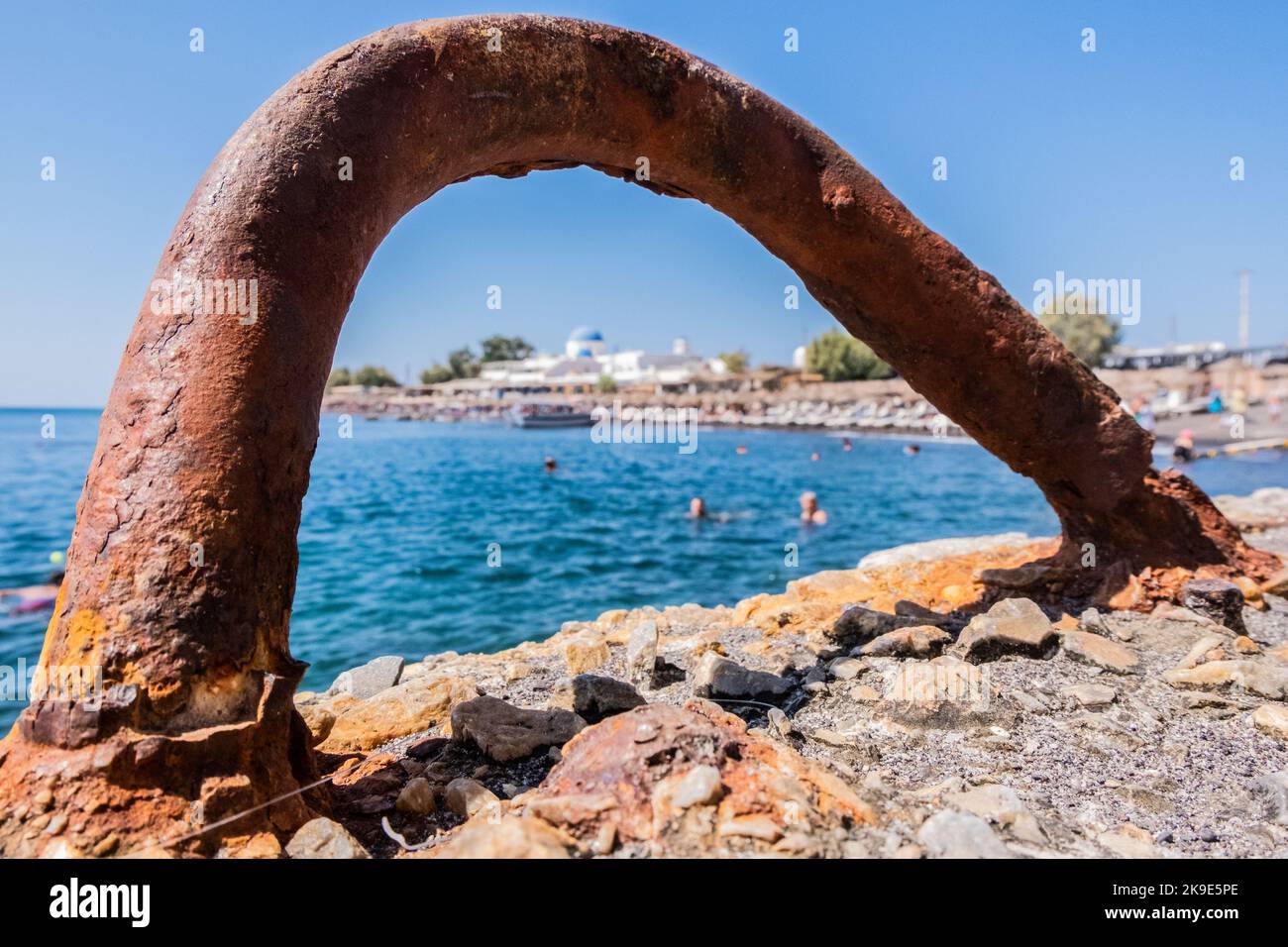 Gancio in metallo arrugginito sul molo con la spiaggia sullo sfondo Foto Stock