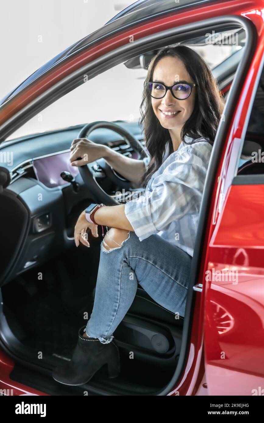 Un cliente soddisfatto siede in una nuova vettura rossa appena prima di acquistarla. Foto Stock