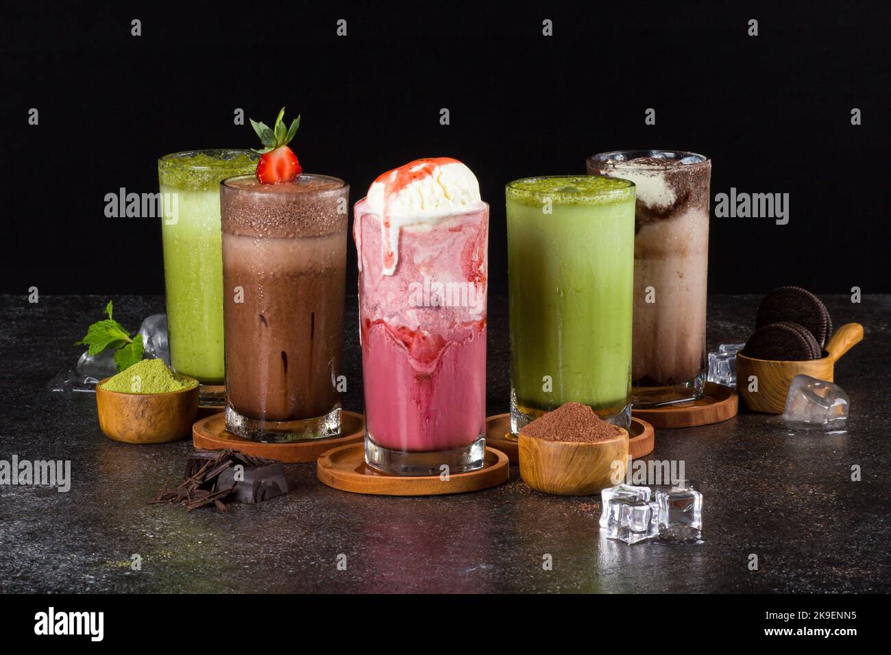 milkshake dolci con cioccolato, caramello, fragola e panna montata su un asse di legno sullo sfondo del tavolo. Foto Stock