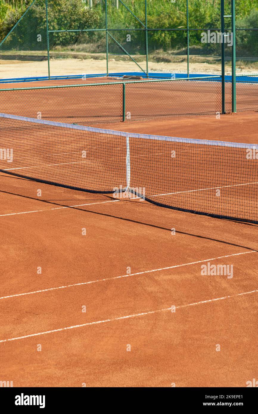 Baseline e al netto di un campo da tennis in terra battuta in una giornata di sole Foto Stock