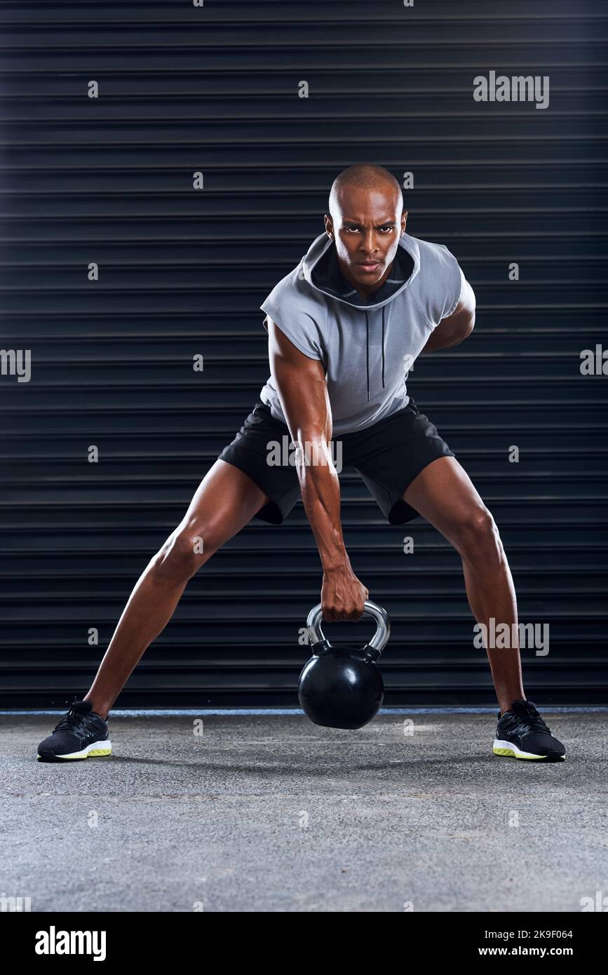 Fate fino a che non diventi parte di chi siete. Un giovane uomo sportivo che lavora fuori con i pesi come parte della sua procedura di esercitazione. Foto Stock