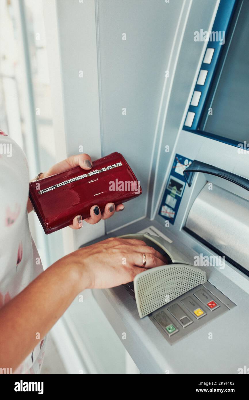 Donna che preleva denaro da bancomat utilizzando carta di debito o di credito utilizzando la tastiera sul terminale atm Foto Stock